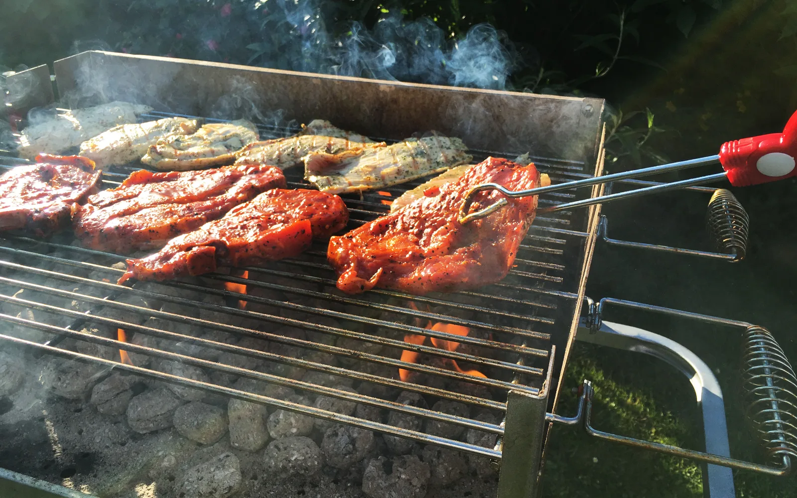 Meat cooking on a charcoal grill over an open fire, showing the wood-fired barbecue cooking method